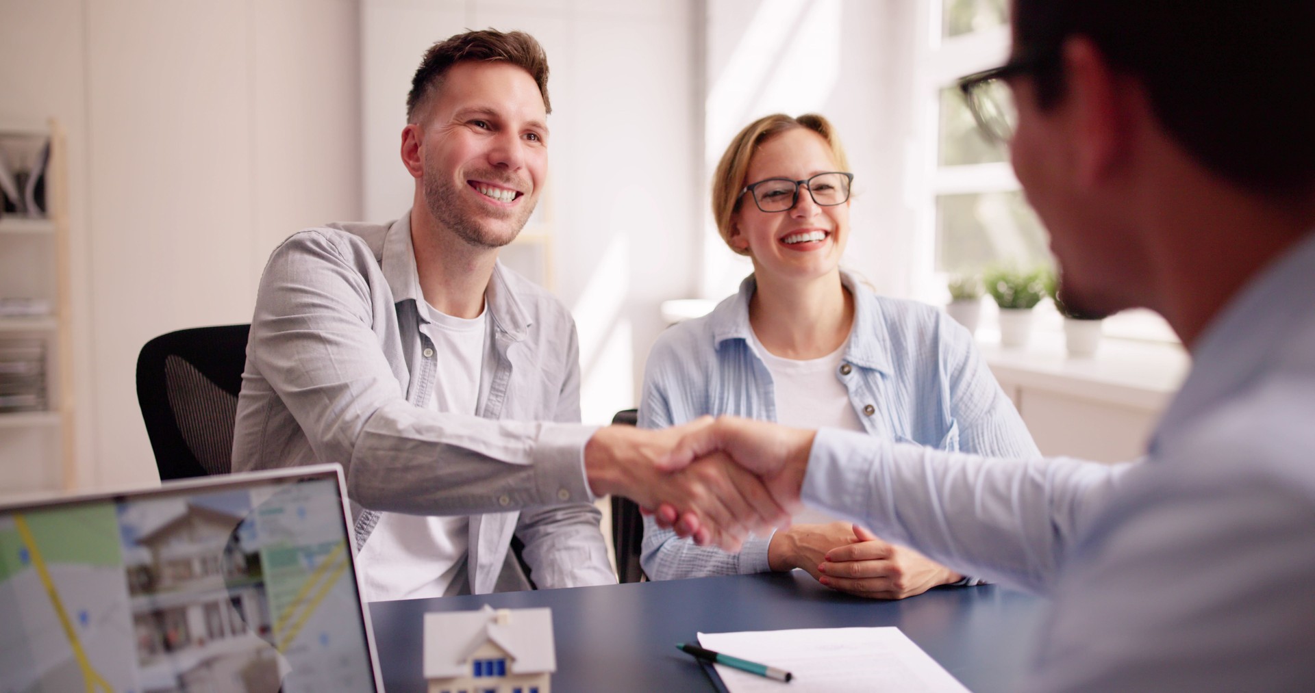 Happy Hispanic Real Estate Agent Shows House to Young Latinx Couple on Laptop