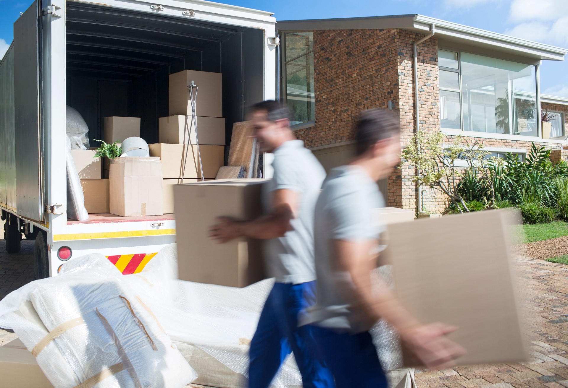 Movers carrying cardboard boxes in driveway